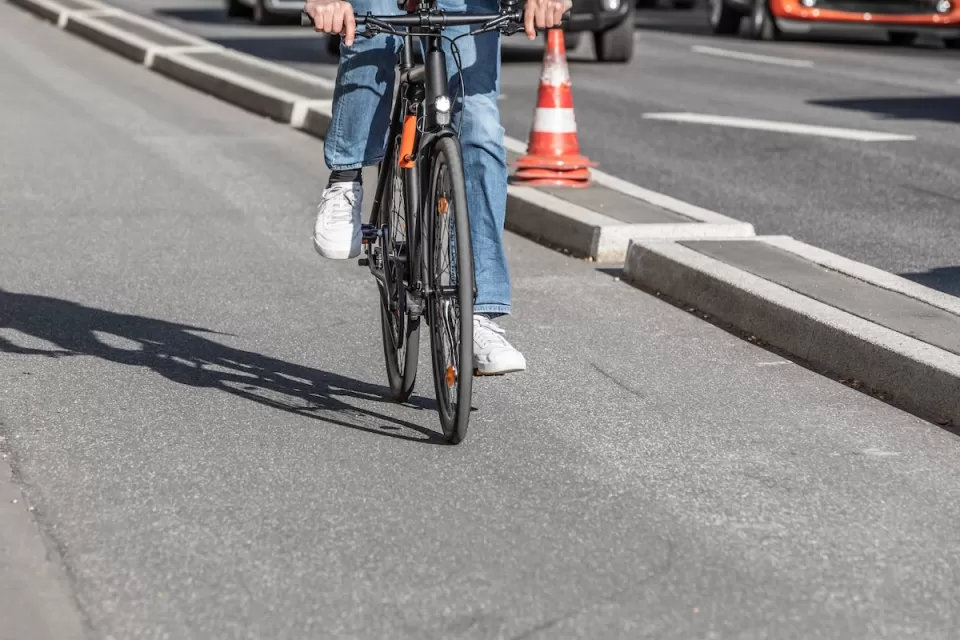 Close-up of person on road bike riding on protected bike lane separated by concrete curb from street.